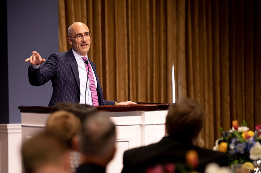 A man is standing at a podium speaking. 